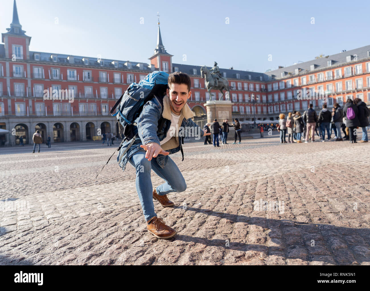 Happy young man traveling around Europe having fun pretending to surf in Plaza de Espa–a, Madrid, Spain. In People Vacations, adventure, backpacking,  Stock Photo