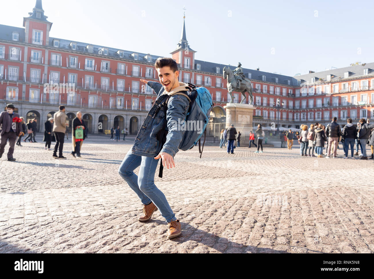 Happy young man traveling around Europe having fun pretending to surf in Plaza de Espa–a, Madrid, Spain. In People Vacations, adventure, backpacking,  Stock Photo