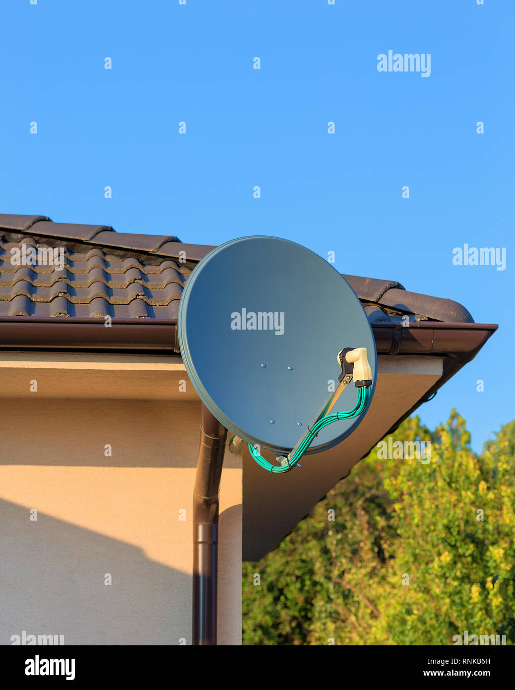 Domestic satellite tv installation under the eaves of home with octo monoblock converter. Residential TV receiver satellite dish with low-noise block  Stock Photo