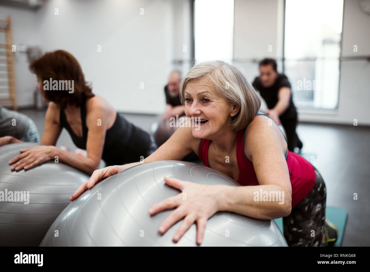 Group of cheerful female seniors in gym doing exercise on fit balls