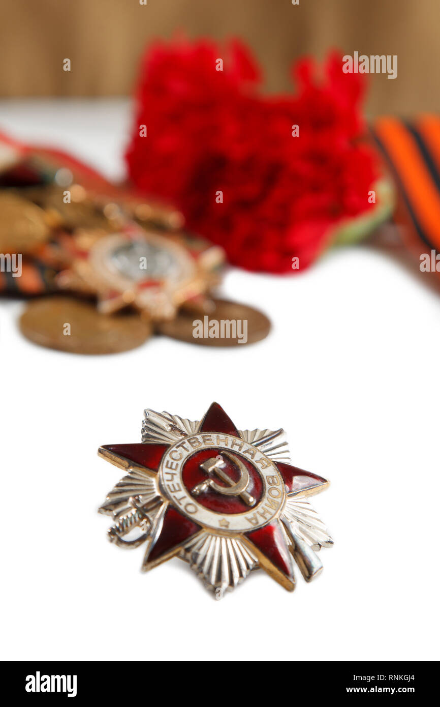 Military cap with red flowers, Saint George ribbon and orders of Great Patriotic war on white background. illustrative editorial.  vertikal shot Stock Photo
