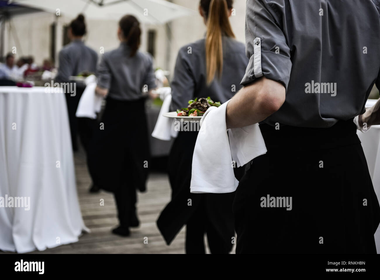 Waiter carrying plates with meat dish on some festive event Stock Photo