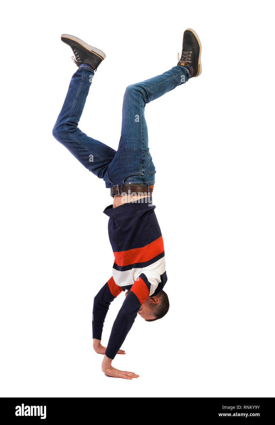 Side view of a man standing on his hands. Stylish guy in a sweater and jeans makes a handstand. backside view of person.  Isolated over white backgrou Stock Photo