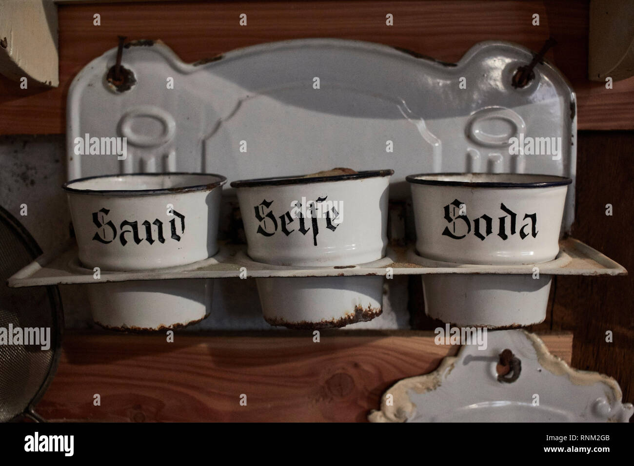 Old enamel holders and shelf with sand, soda and soap. Germany Stock Photo
