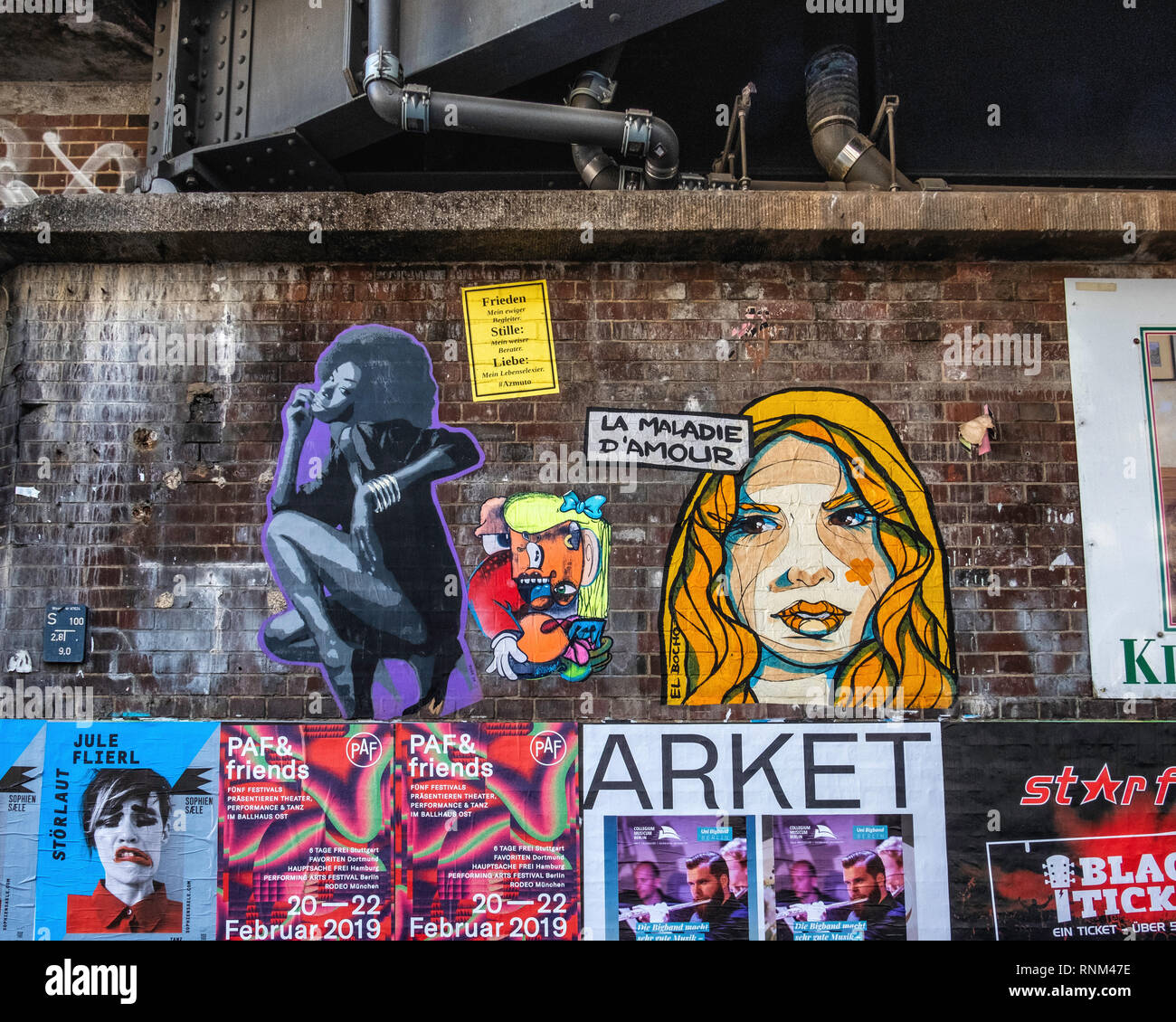 Berlin, Hackescher Markt. Railway station viaduct, old brick wall, pipes, posters and street art paste-ups Stock Photo