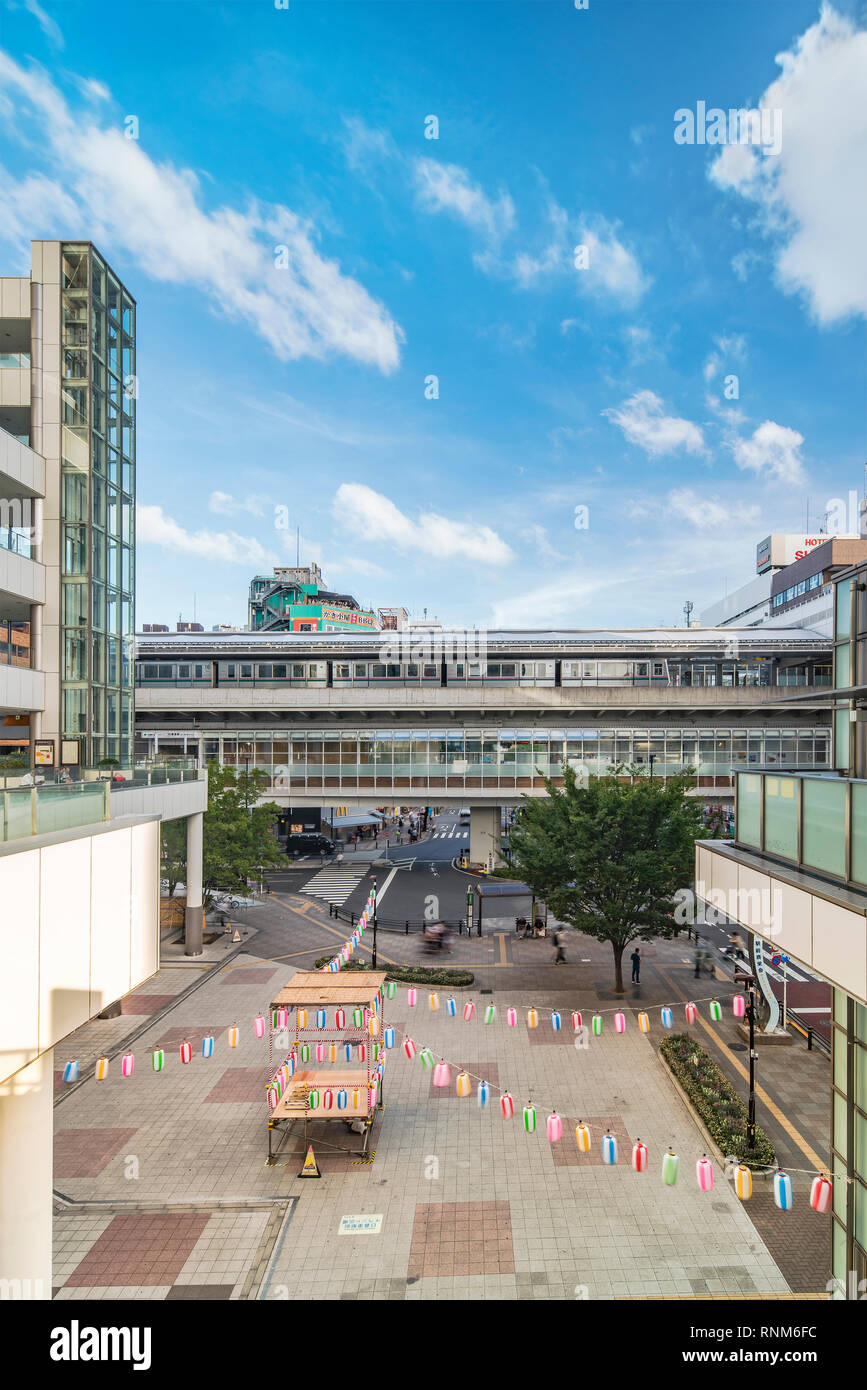 View of the square in front of the Nippori train station decorated for the Obon festival in the summer with a yagura tower and paper lanterns in the A Stock Photo