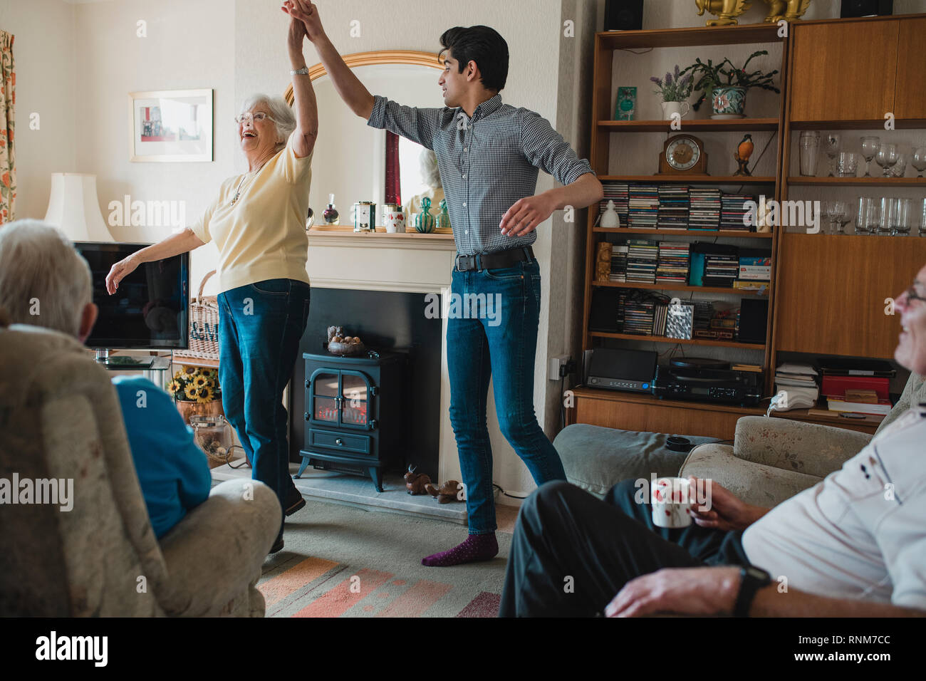 Senior woman is dancing in the living room with her teenage grandson. Stock Photo