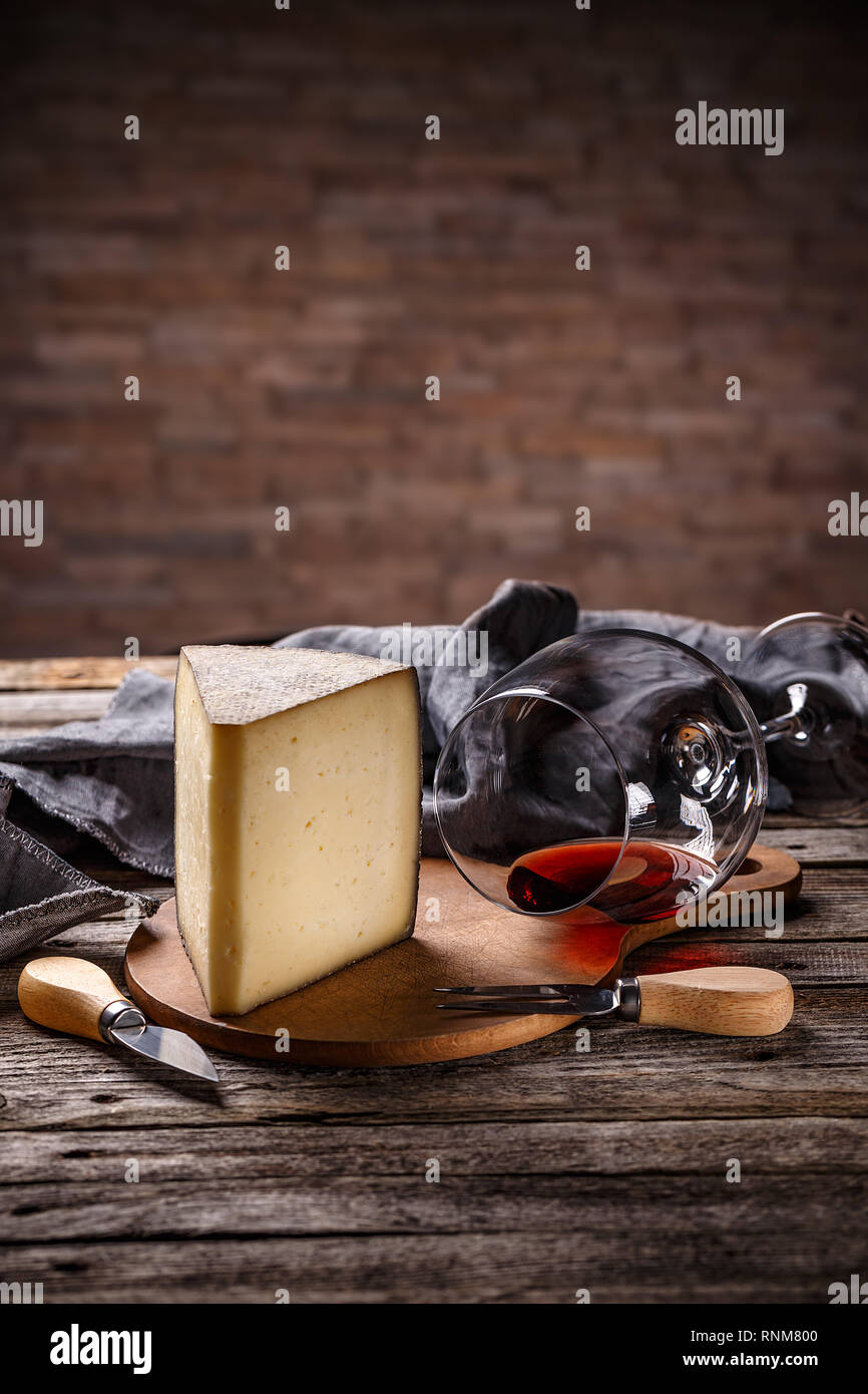 Wedge of cheese with glass of red wine on vintage wooden background Stock Photo