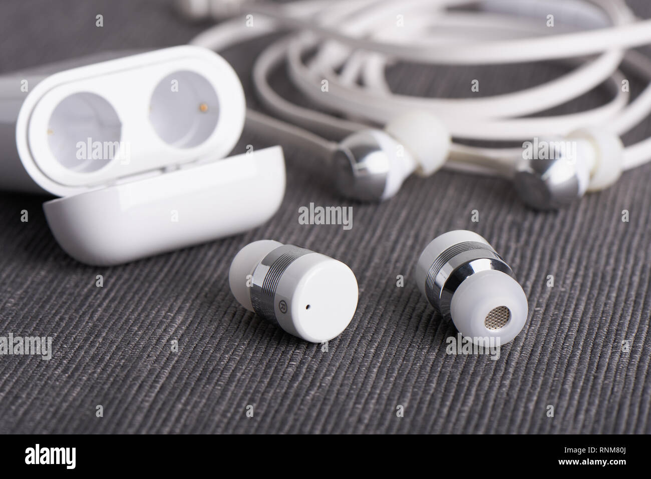 wireless cordless bluetooth earbuds with chargeable case on a background of cable earphone Stock Photo
