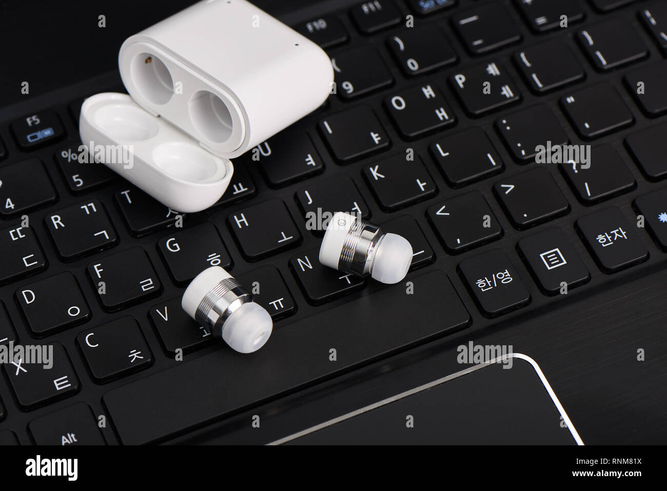 wireless cordless bluetooth earbuds with chargeable case on a keyboard of laptop computer Stock Photo