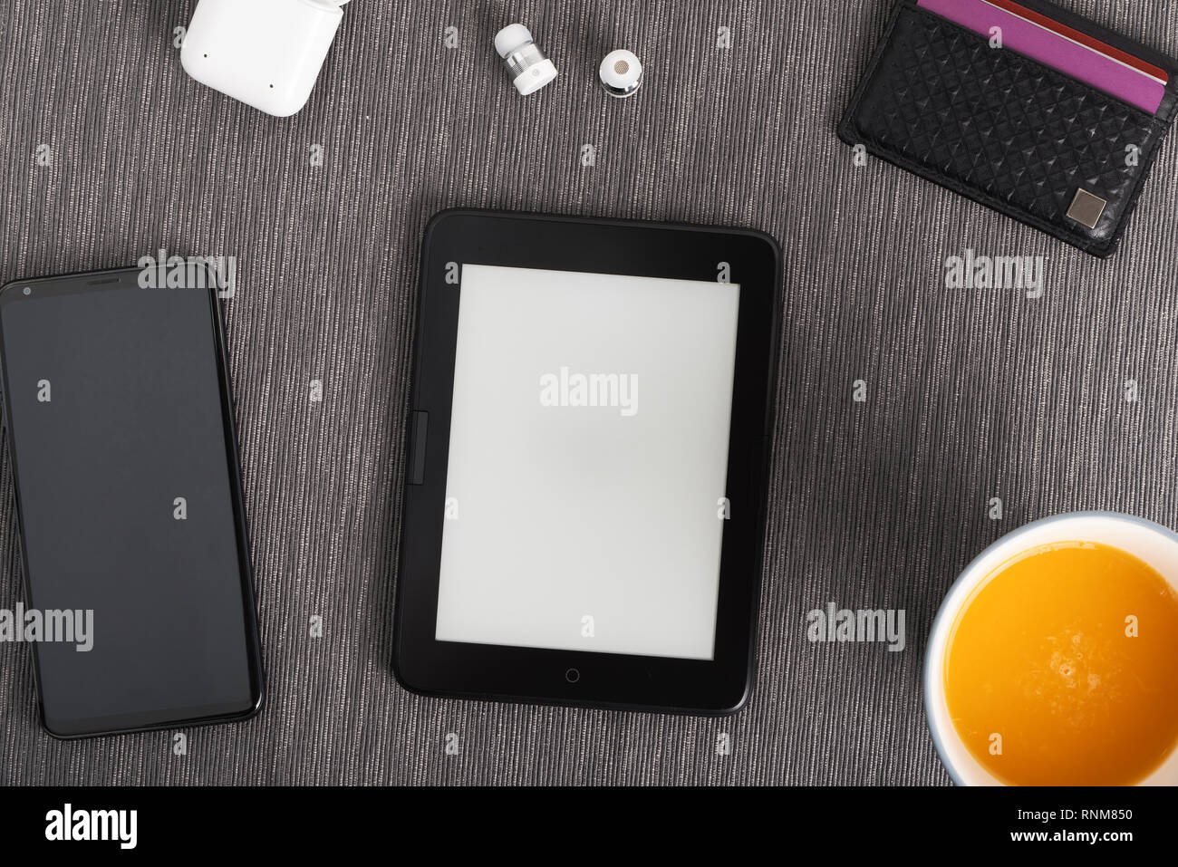 e-book with smartphone, card holder, wireless earbuds and a cup of orange juice Stock Photo