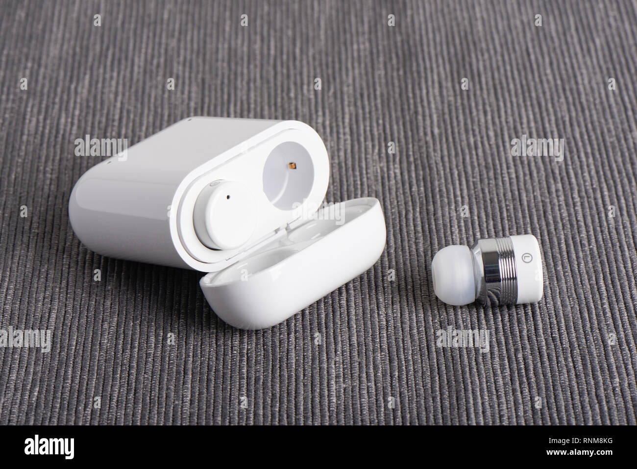 wireless cordless bluetooth earbuds with chargeable case on a fabric background Stock Photo