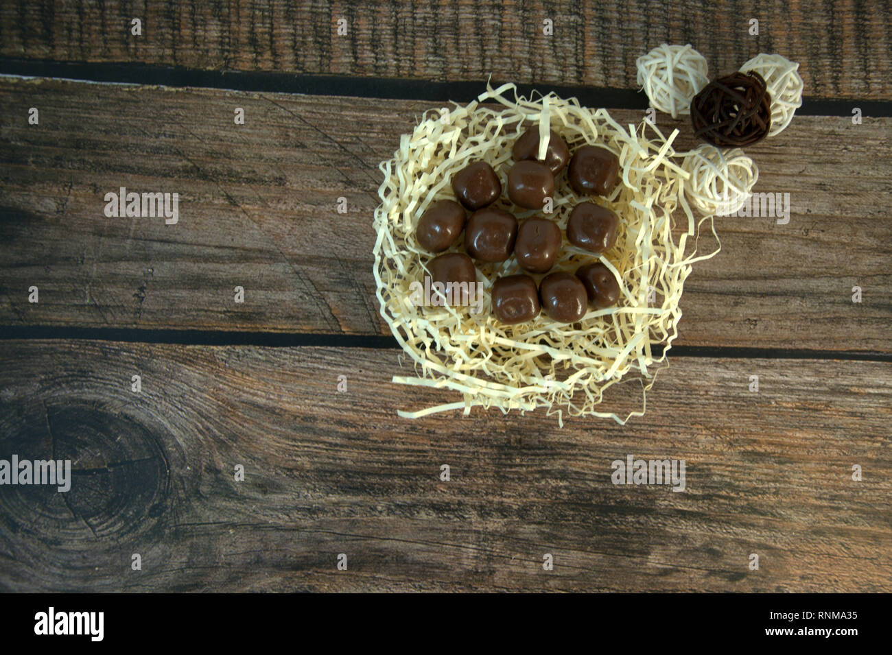 A Nest Of Straw With Chocolates And And Decorative Balls On A