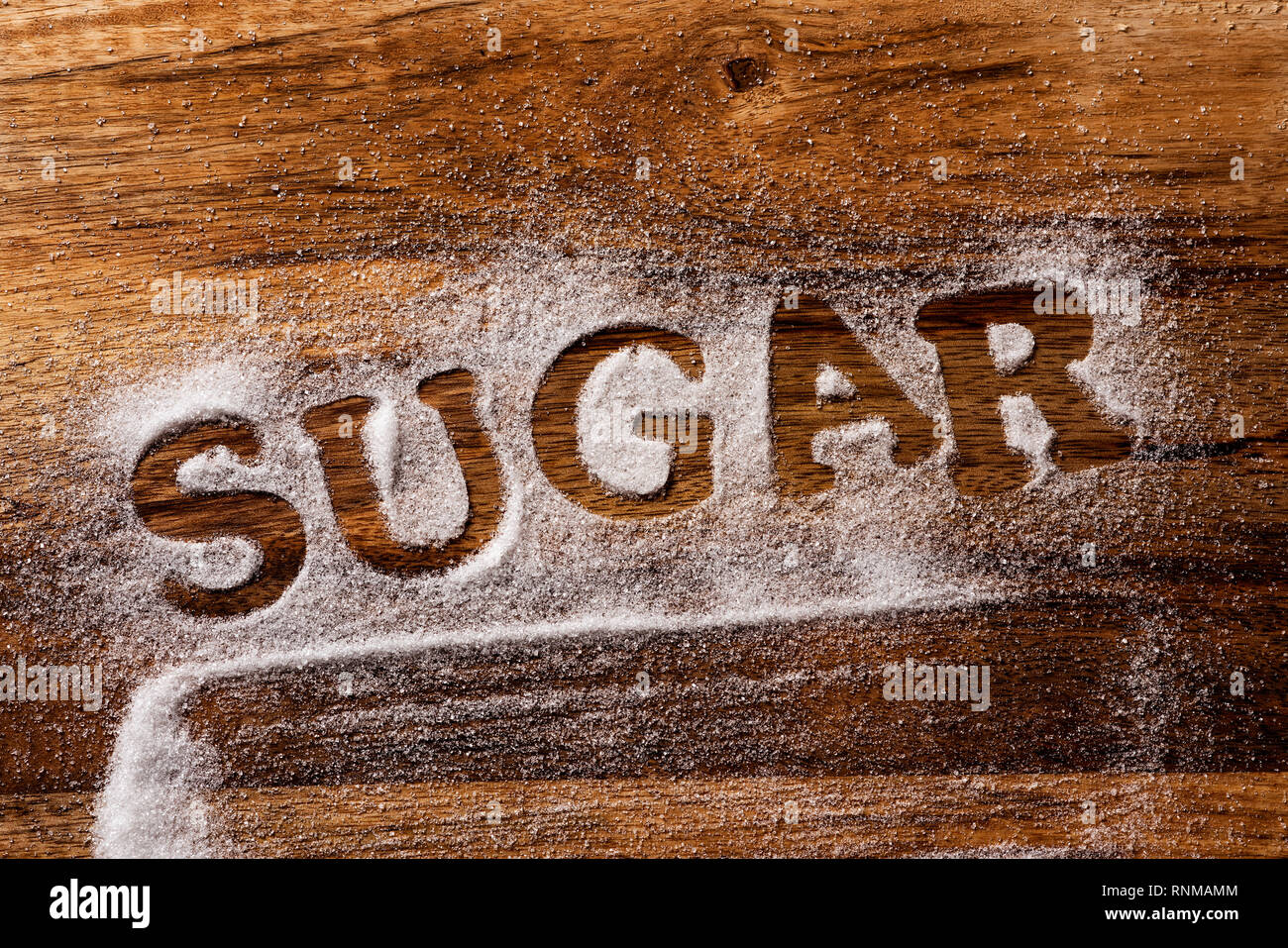 high angle view of a wooden table sprinkled with sugar where you can read the word sugar Stock Photo