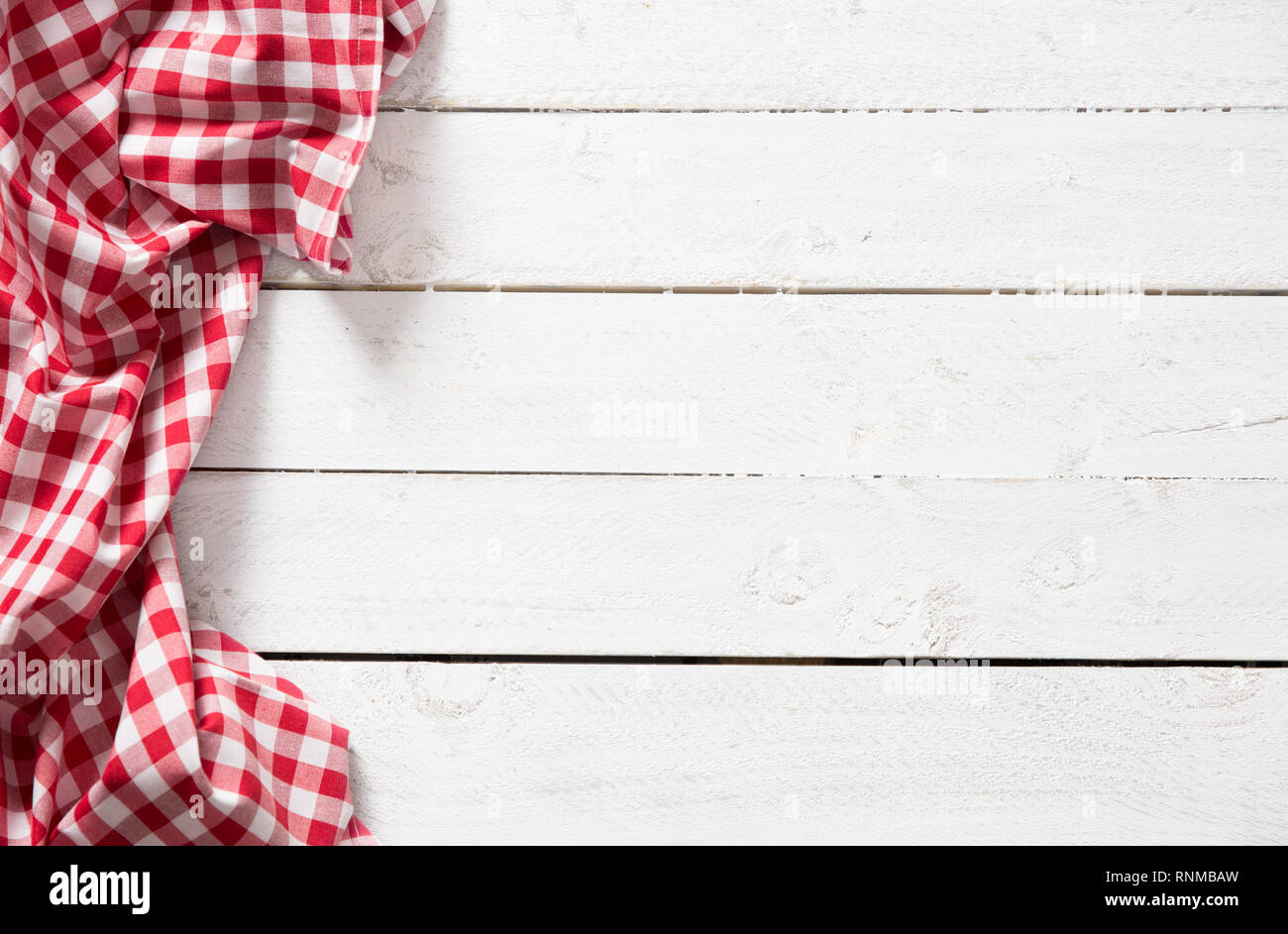 Red checkered kitchen tablecloth on wooden table. Stock Photo