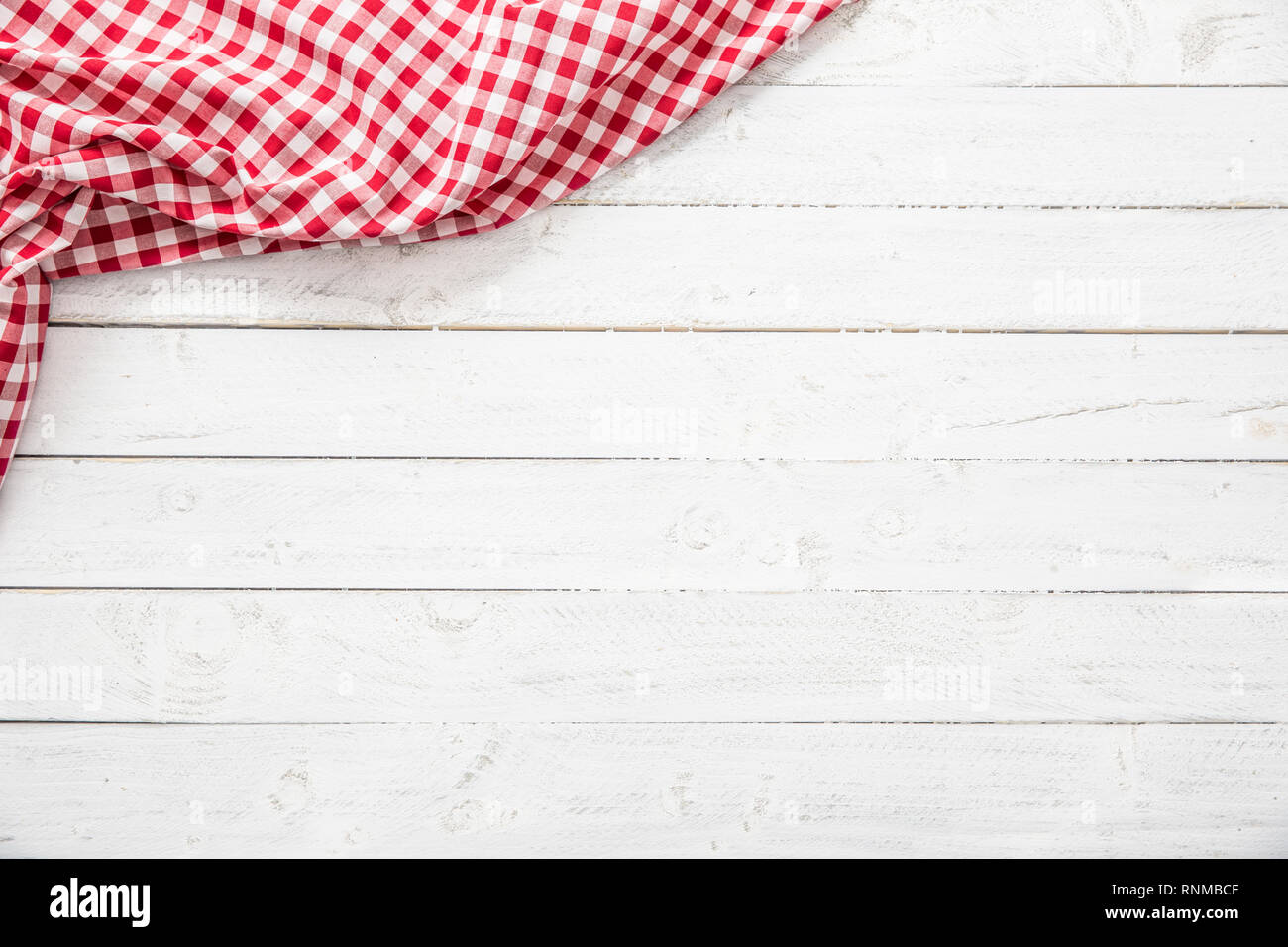 Red checkered kitchen tablecloth on wooden table. Stock Photo