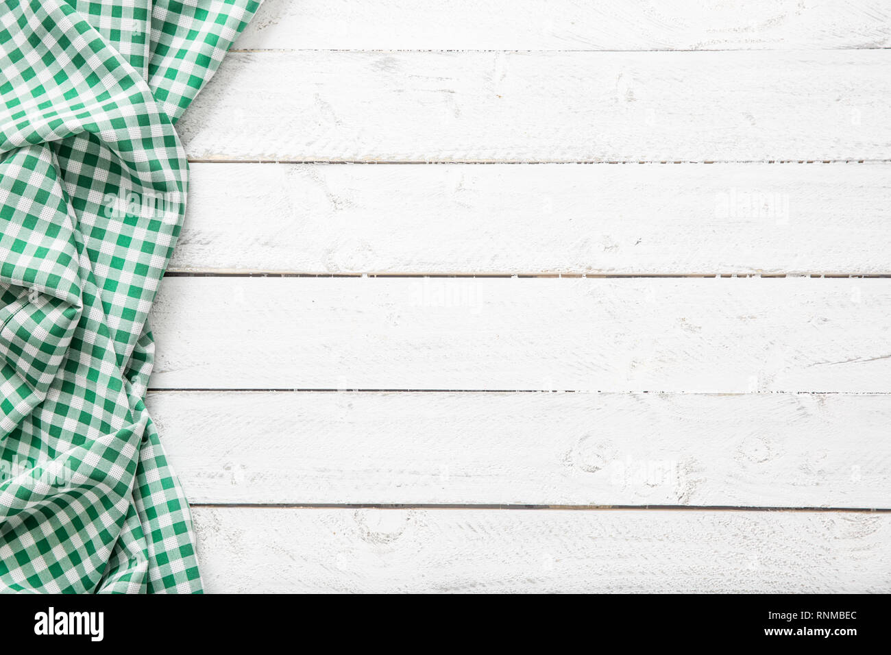 Green checkered kitchen tablecloth on wooden table. Stock Photo