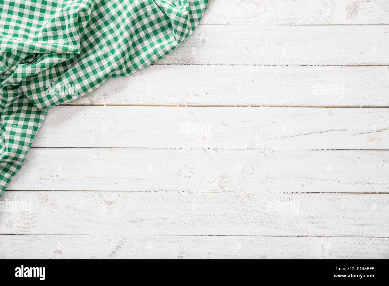 Green checkered kitchen tablecloth on wooden table. Stock Photo