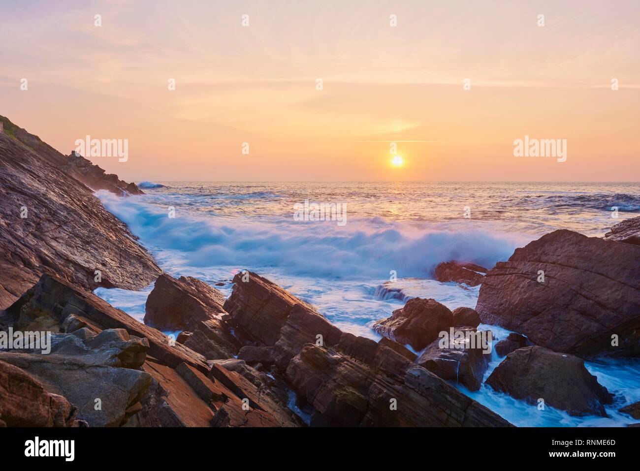 Breaking waves at rocky coast at sunset, atlantik ocean, near Hondarribia, Basque country, Spain Stock Photo