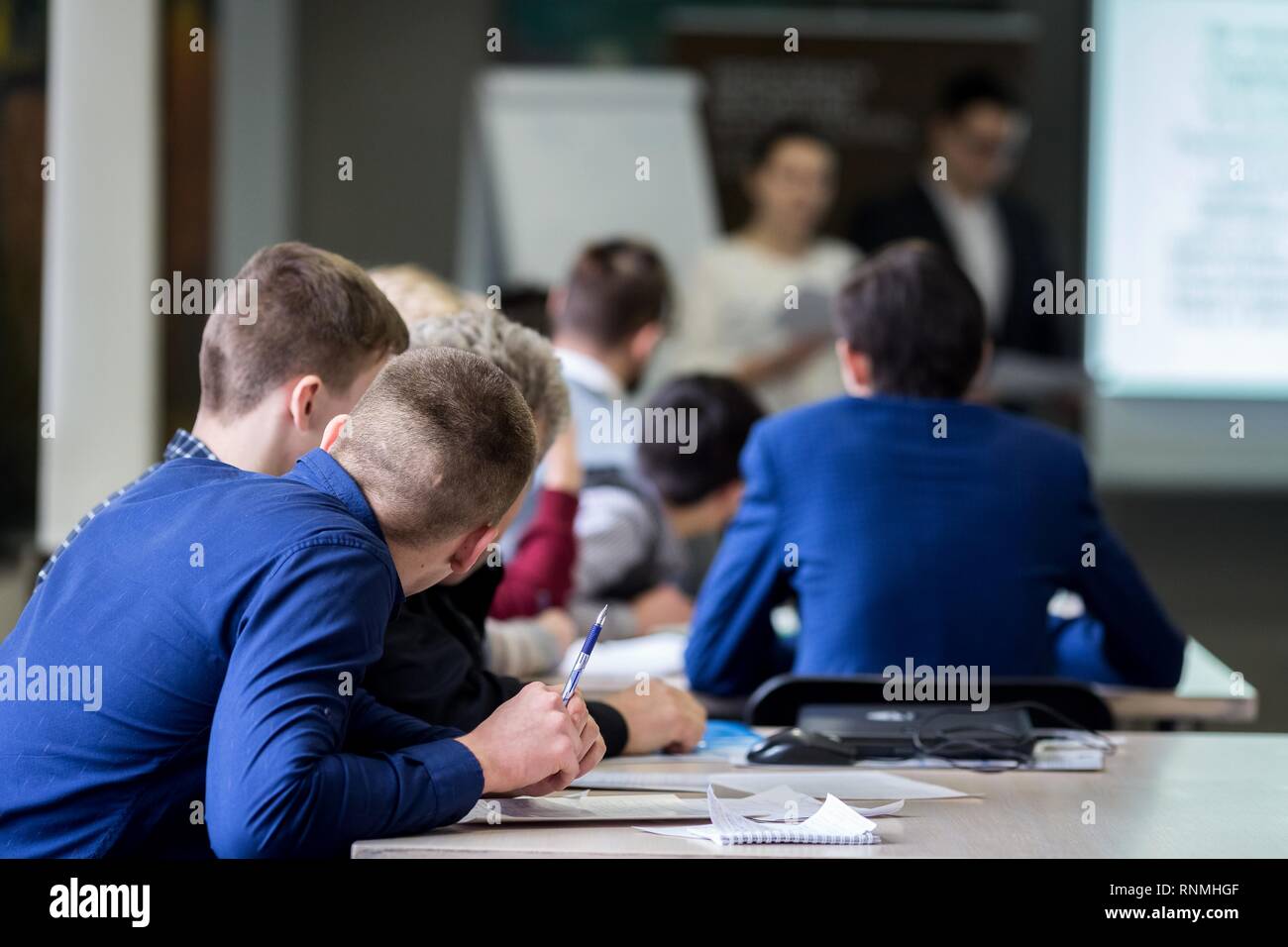 Brainstorming, young students of 18-20 years old, vividly discuss the lecture of teachers at the table, take an exam, write and answer control questio Stock Photo
