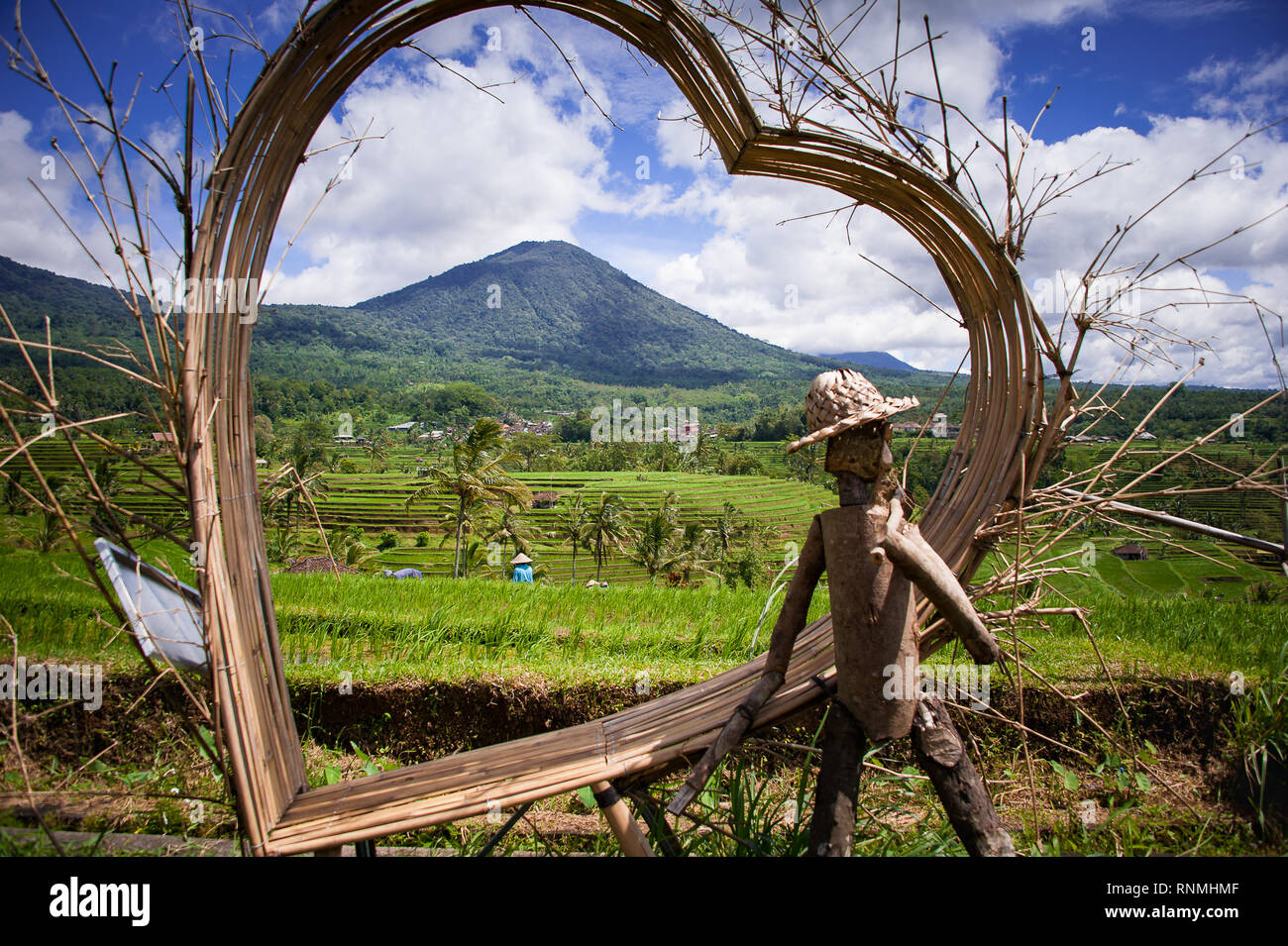 Jatiluwih Rice Terraces, Bali. Colourful scene viewed through heart shaped, rattan sculpture with plantation workers, lush green fields and mountains Stock Photo