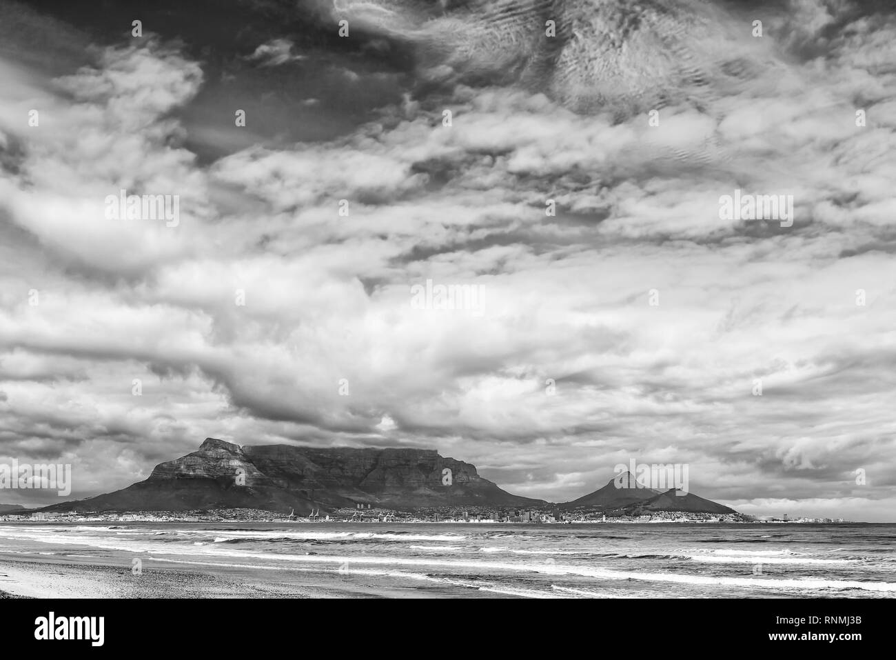 The Cape Town Central Business District and Table Mountain as seen across Table Bay from Dolphin Beach. Monochrome Stock Photo