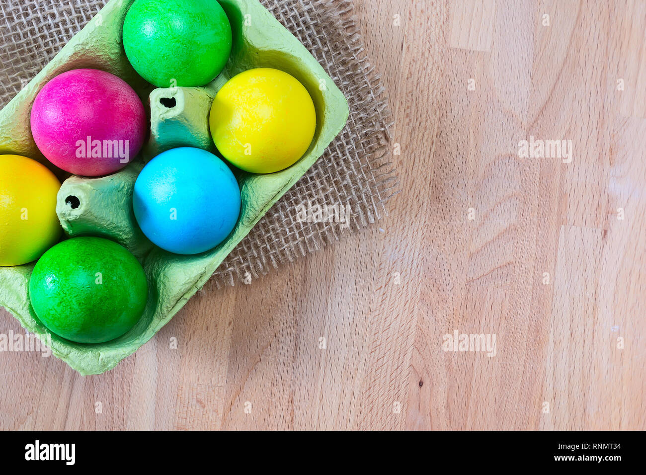 Brightly colored bow decorated easter eggs in egg carton holder, holiday background Stock Photo