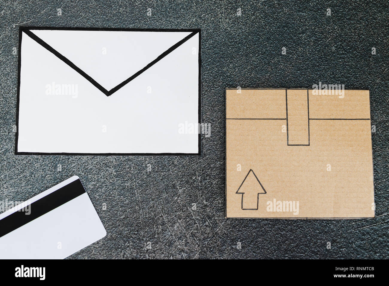 cardboard parcel with email envelope and payment card on concrete desk