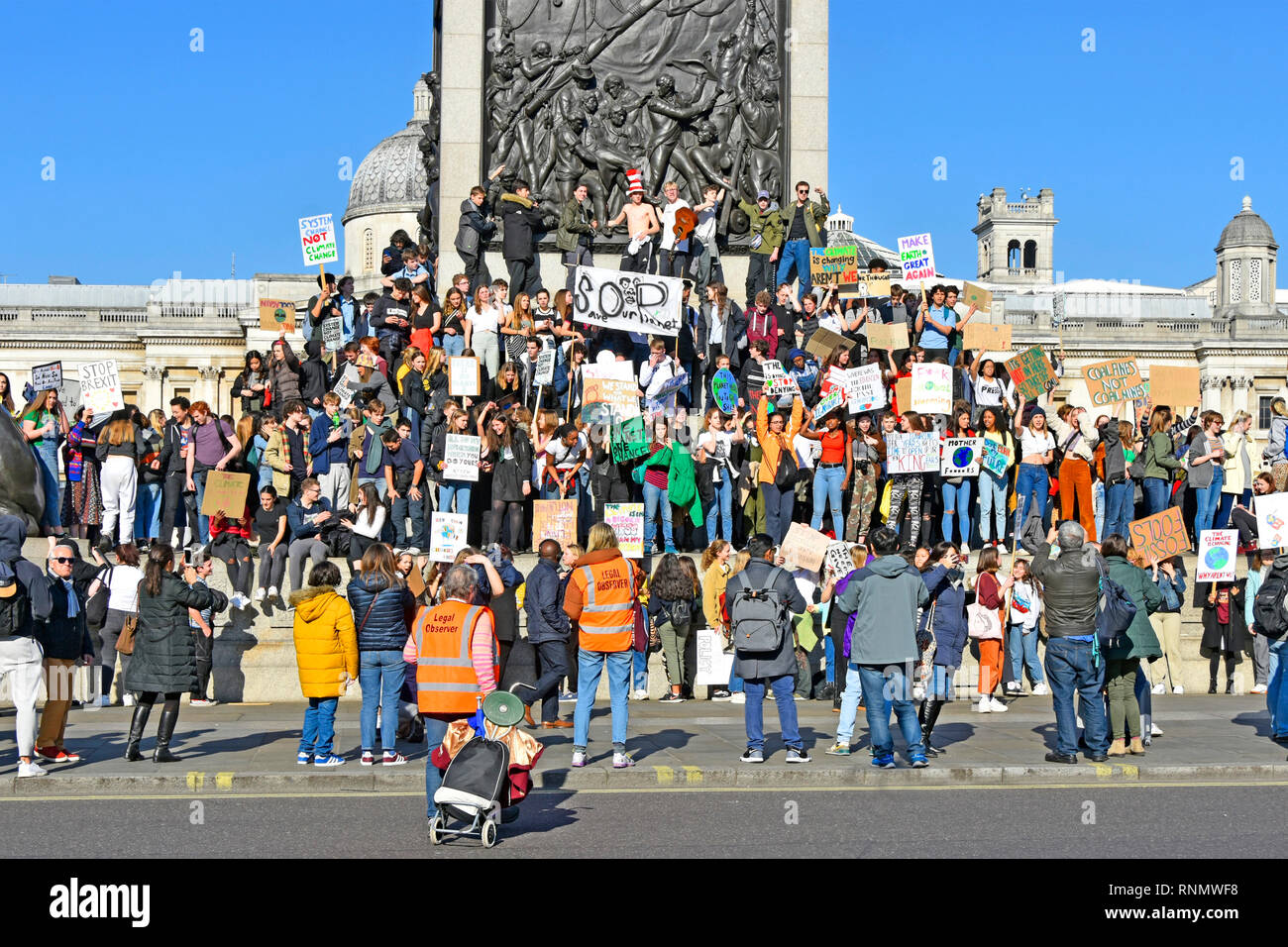 Teenager groups of school children kids miss school to strike & protest on climate change wave placard & chant from  Nelsons Column London England UK Stock Photo