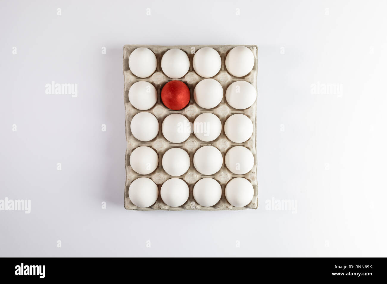 with white eggs and one red easter egg on white background. Stock Photo