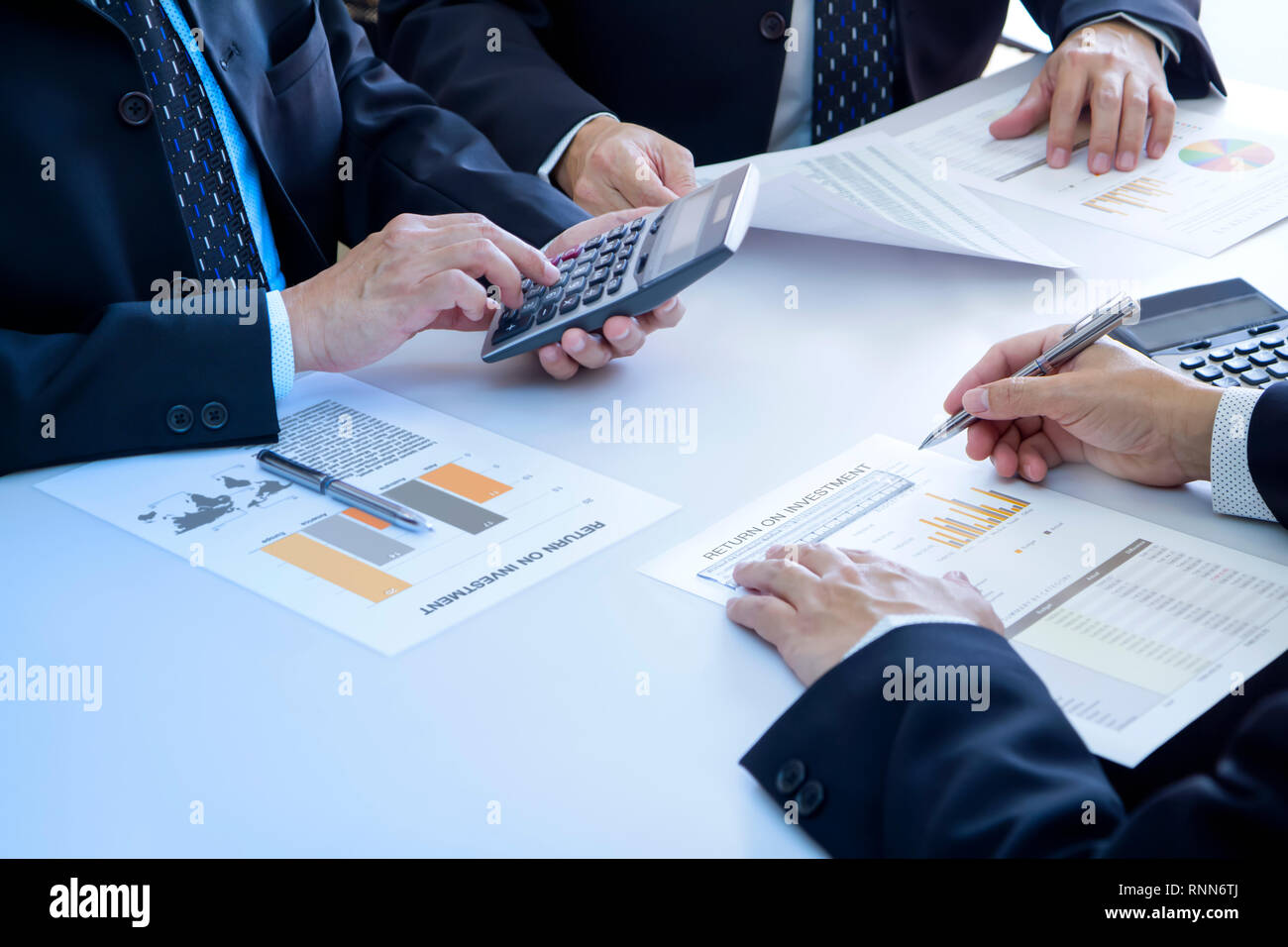 Businessmen are deeply reviewing a financial reports for a return on investment or investment risk analysis. Stock Photo