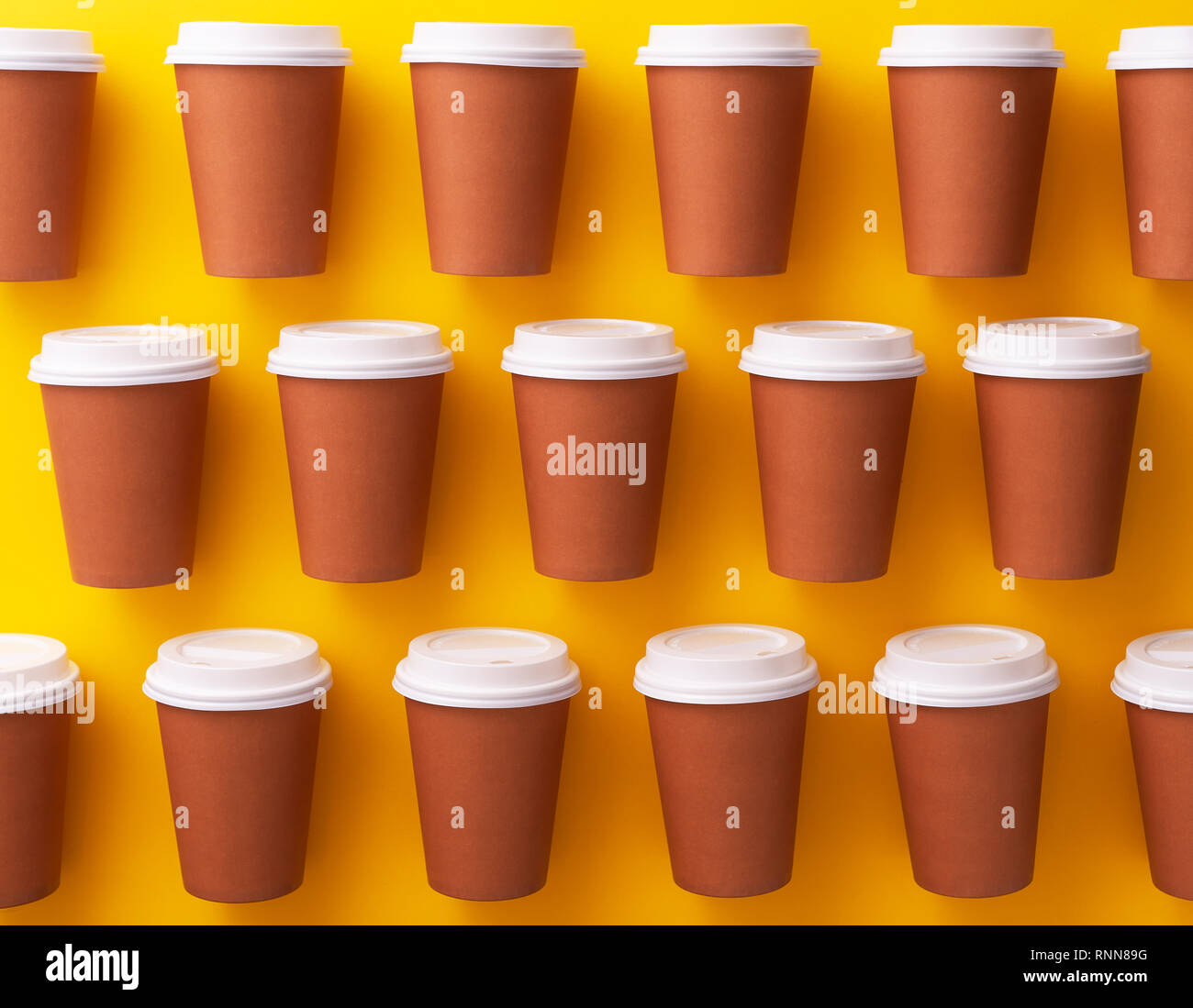 Multiple disposable coffee cups organized over yellow background Stock