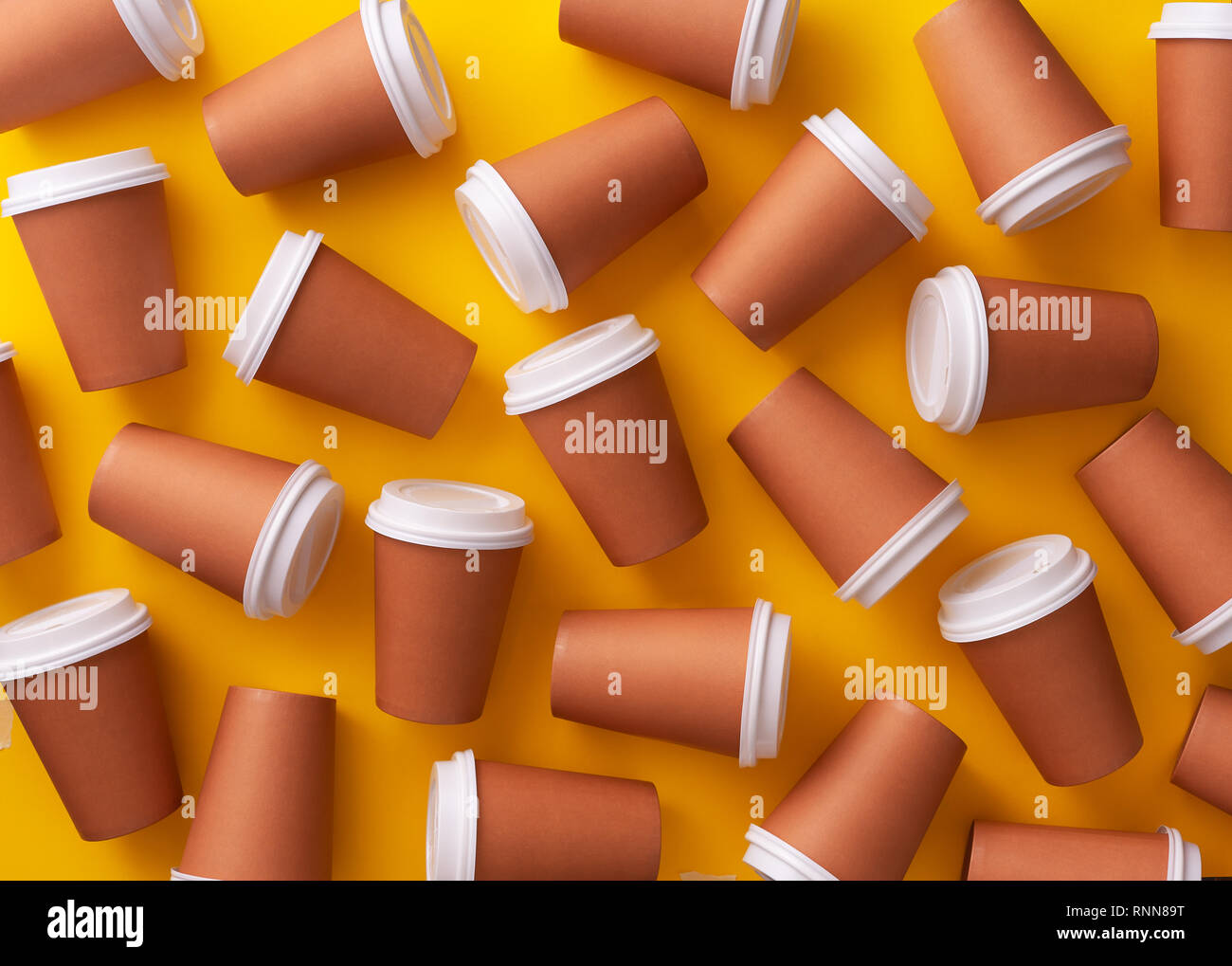 Multiple disposable coffee cups organized over yellow background Stock