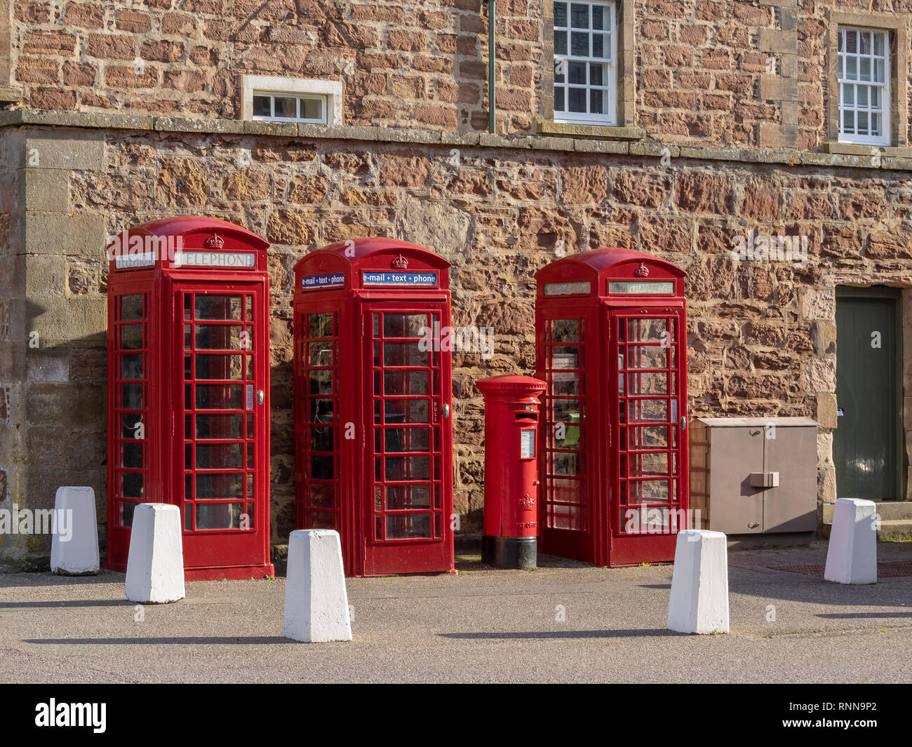 Three British red telephone boxes or kiosks and one red post box or pillar box, Fort George, near Inverness, Scotland Stock Photo