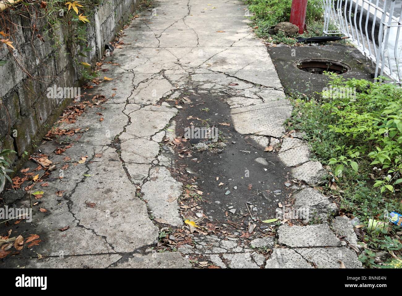 Dangerous city sidewalk in Manila, Philippines. Hazardous holes and