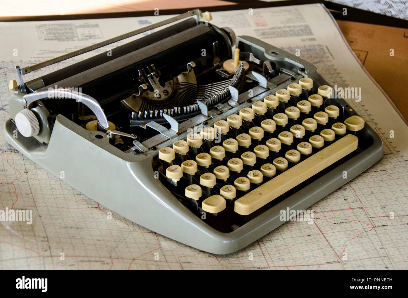 An old typewriter sitting on a map in an office Stock Photo