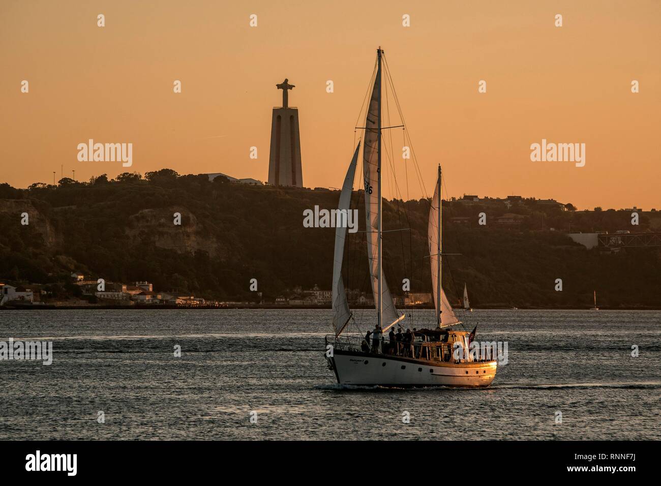 Evening atmosphere at the Rio Tejo with sailboat and Jesus statue Cristo Rei, Lisbon, Portugal Stock Photo