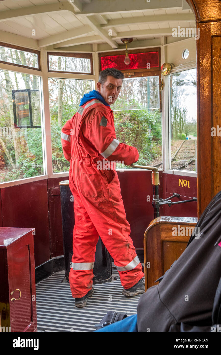 Engineer driving the heritage tram using the brake lever to control the stopping of the team. Stock Photo