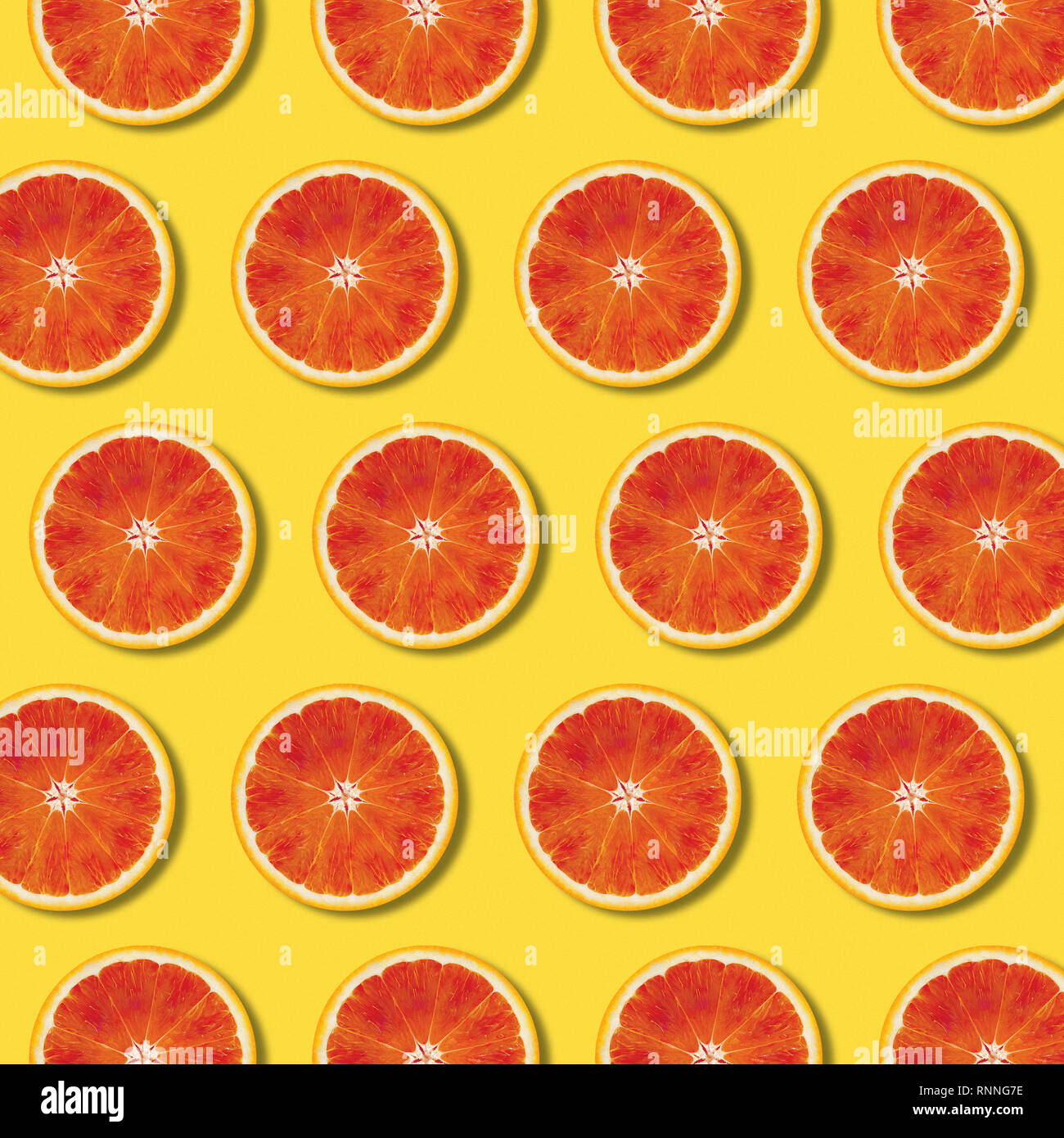 Red orange slices pattern on yellow color background. Minimal flat lay top view food texture Stock Photo