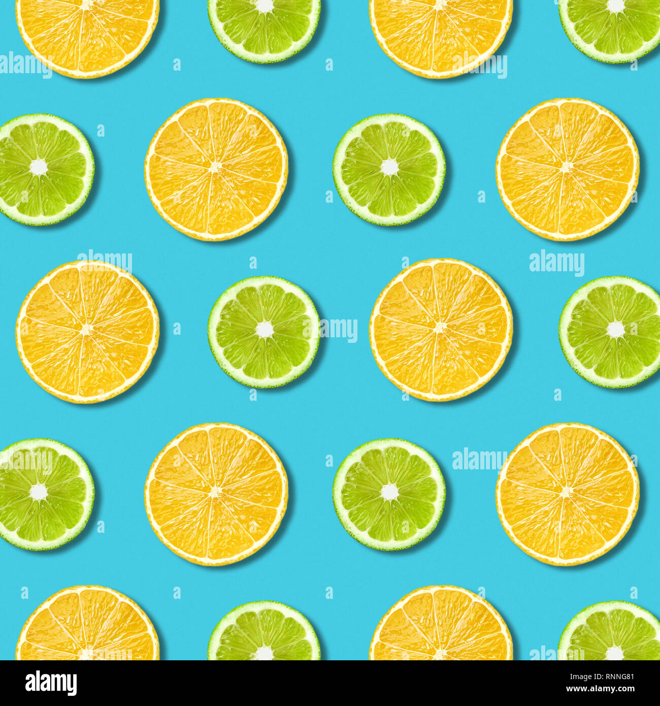 Vibrant lemon and green lime slices pattern on turquoise color background. Minimal flat lay top view food texture Stock Photo