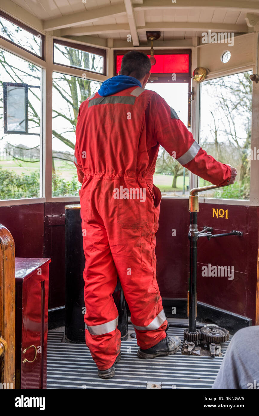 Engineer driving the heritage tram using the brake lever to control the stopping of the team. Stock Photo