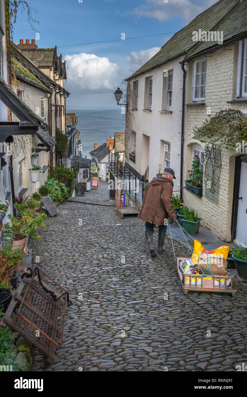 A man delivers winter supplies by a traditional sledge to the residents in the High Street at Clovelly in North Devon. Set into a steep hillside, sled Stock Photo