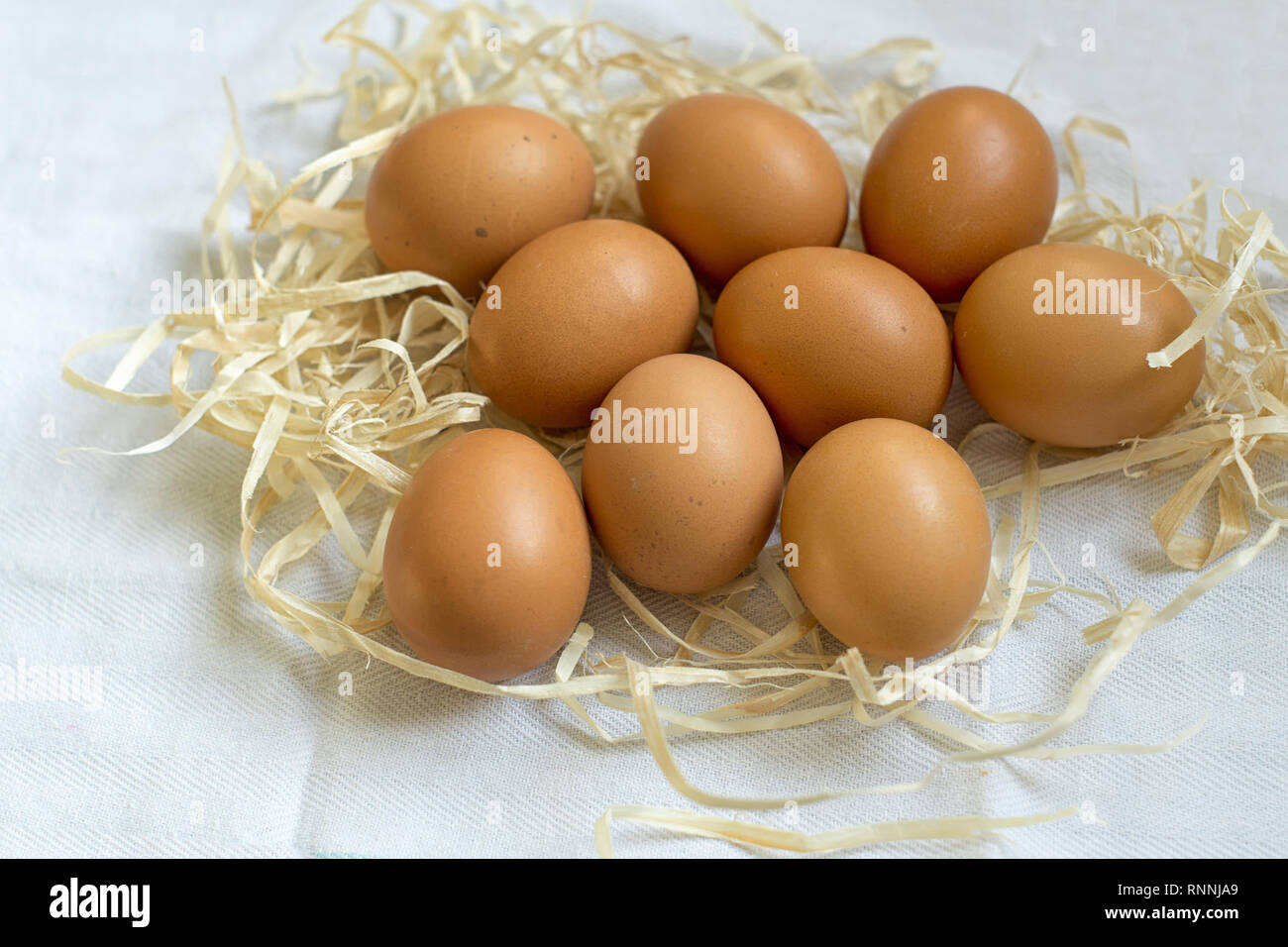 Fresh organic eggs in straw on white cloth Stock Photo