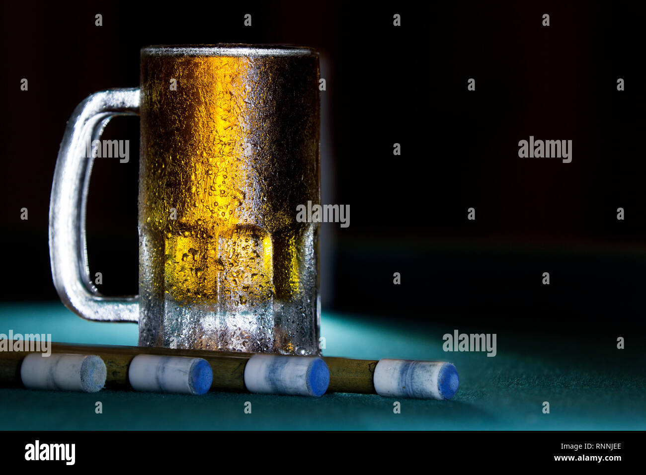 close up isolated cold frozen beer mug with billiard cues on black background Stock Photo