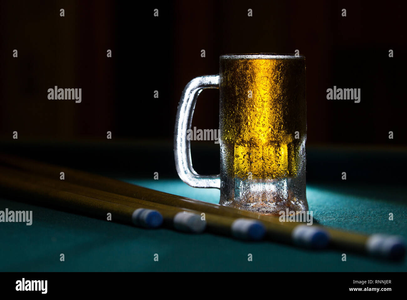 isolated cold frozen beer mug with billiard cues on black background Stock Photo