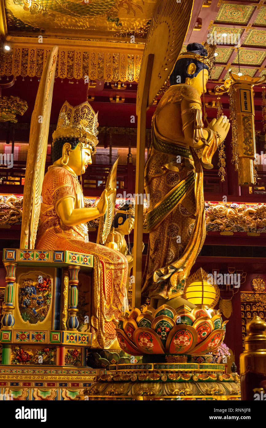 Buddha Tooth Relic Temple. Buddha Maitreya on left in Main Prayer Hall, Bodhisattva on right foreground. Singapore. Stock Photo