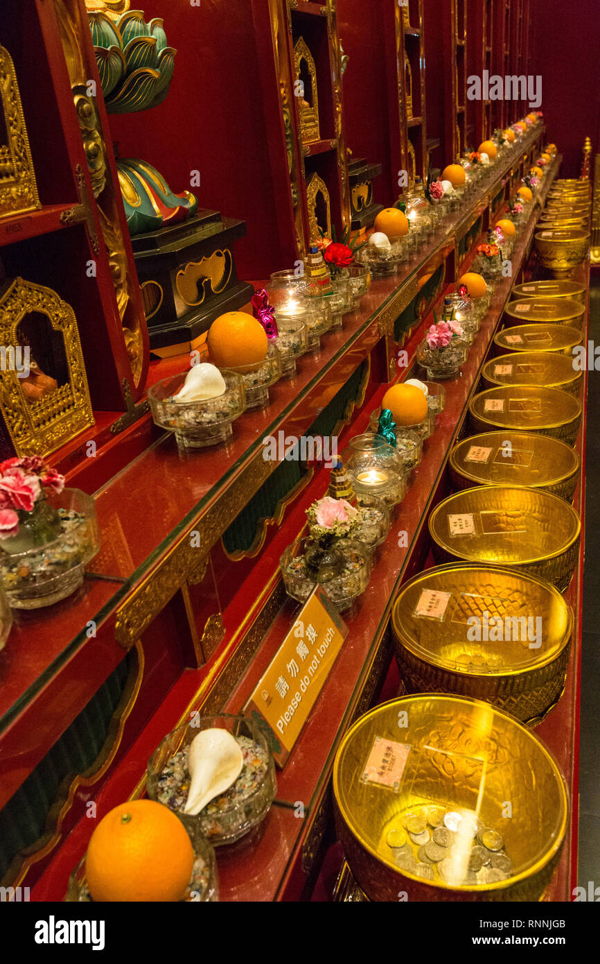 Buddha Tooth Relic Temple, Singapore.  Bowls for Receiving Coin Offerings for the Temple.  Other donations line the wall. Stock Photo