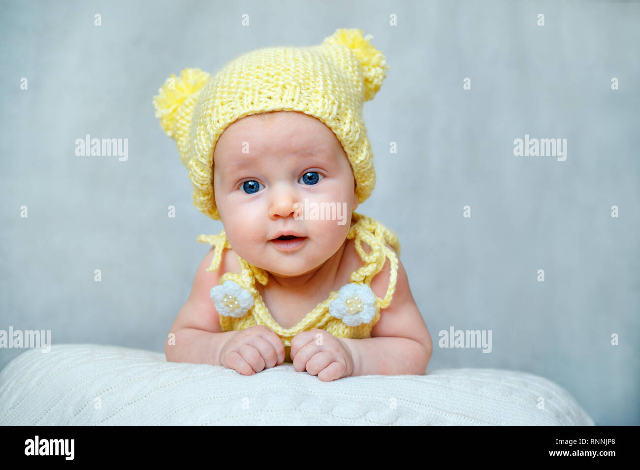 Portrait of a cute newborn baby girl in yellow knitted hat Stock Photo