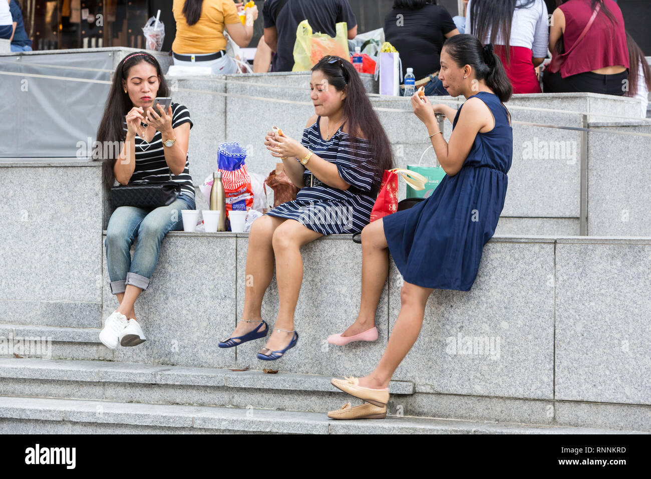 Women Relaxing outside ION Mall, Singapore, Orchard Road Street Scene. Stock Photo