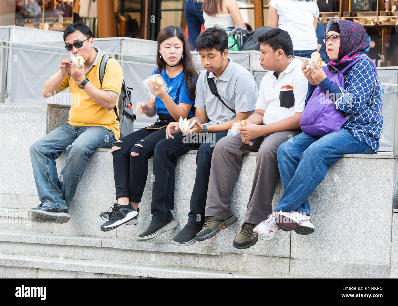 Singapore, Shoppers Eating outside the ION Mall, Orchard Road Street Scene. Stock Photo